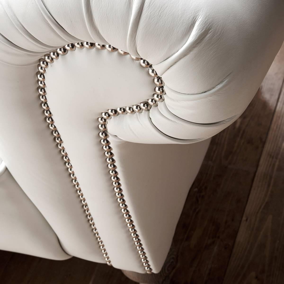 Detailed studded nail work on white leather upholstery restoration