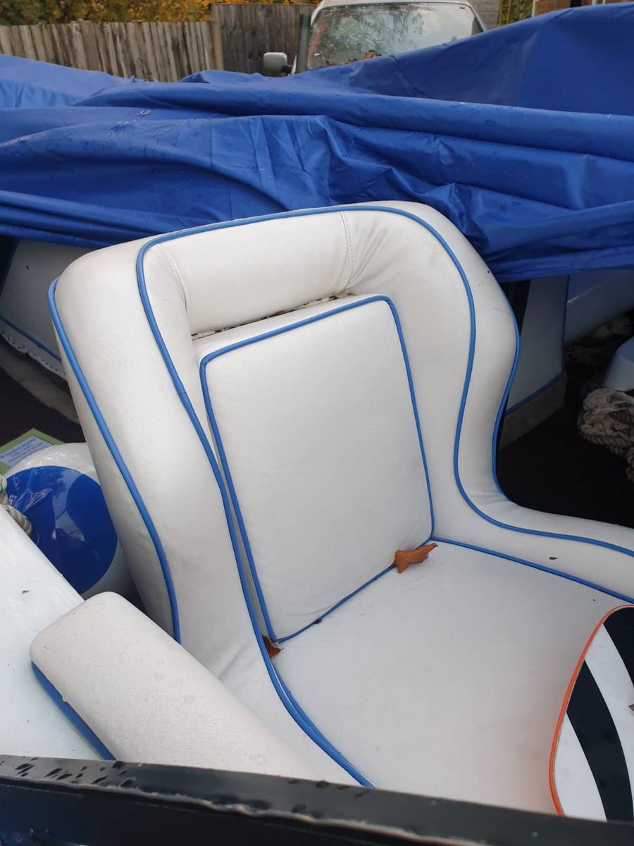 Worn MasterCraft captain's chair with deteriorated white vinyl and blue piping