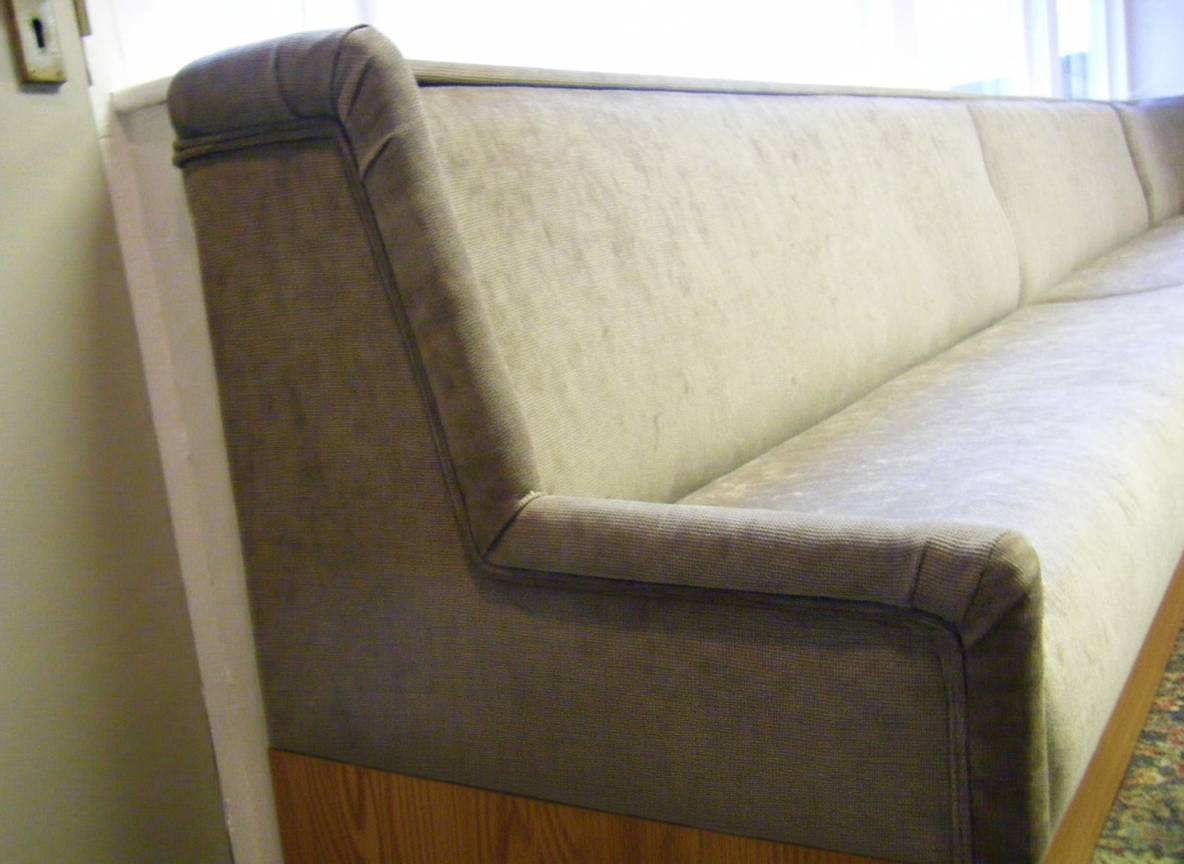 Corner detail of finished bench seating in neutral fabric with piped edges