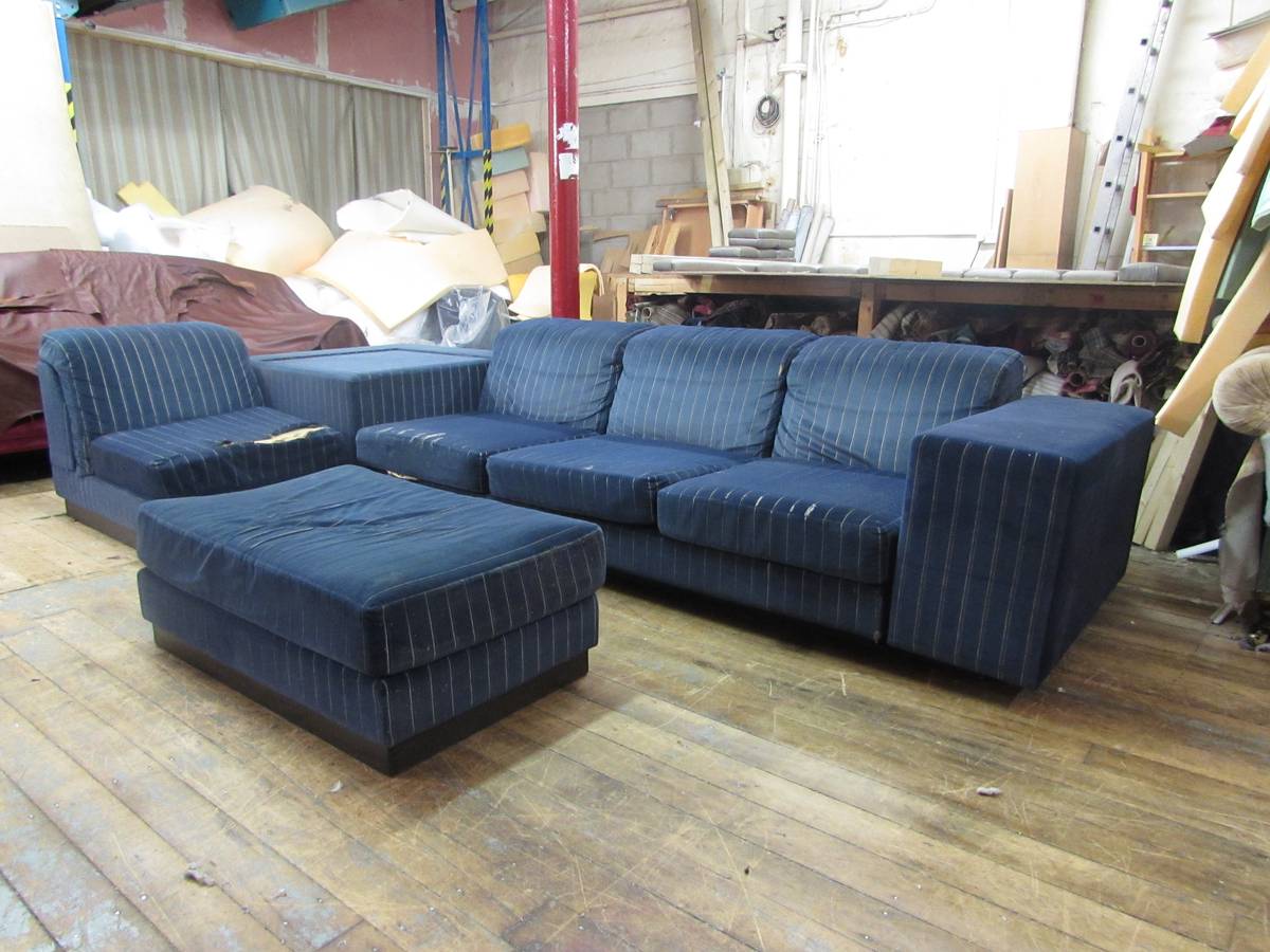 Worn navy pinstripe modular sofa with ottoman in workshop