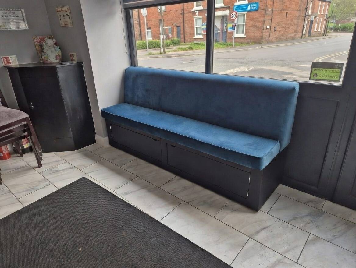 Commercial restaurant bench seating upholstered in blue velvet with dark base and storage drawers